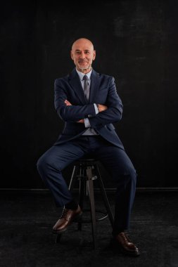 Siyah arka planda orta yaşlı bir adamın stüdyo resmi. Tecrit edilmiş arka planda takım elbiseli kel ve sakallı bir adam. Tam yol ileri. Boşluğu kopyala. 