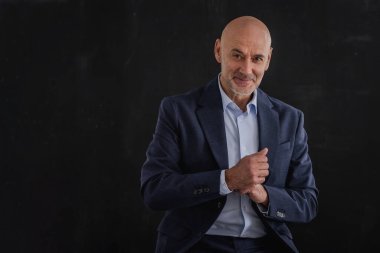 Gülümseyen iş adamının takım elbise giyip izole edilmiş gri arka planda dikilirken çekilmiş görüntüsü. Boşluğu kopyala.