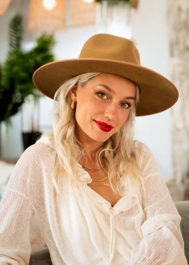 Sarı saçlı, şapkalı ve kırmızı rujlu bir kadının portresi. Çekici kadın kameraya gülümsüyor.. 