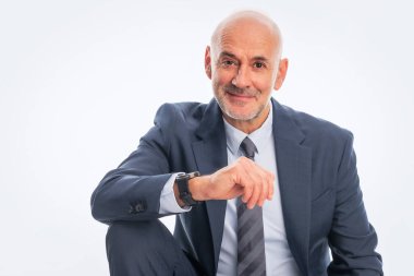 Orta yaşlı işadamı takım elbise giyip izole edilmiş arka planda kravat takıyor. Beyaz arka planda oturan kendine güvenen bir adam. Boşluğu kopyala.