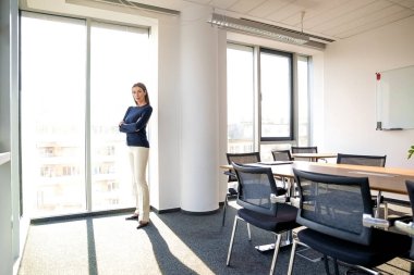 Kendine güveni tam bir iş kadını modern bir ofiste kameraya bakıyor..