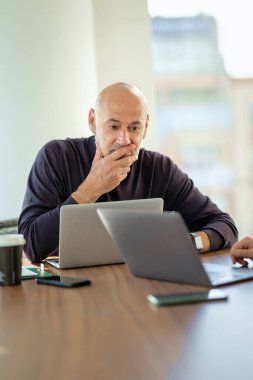 Masada oturup dizüstü bilgisayarını kullanan işadamı suratını merak ediyorum. Modern bir ofiste çalışan orta yaşlı profesyonel bir adam.. 