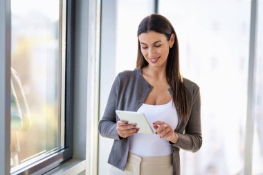 Ofiste elinde dijital tabletle duran bir iş kadını. Modern bir ofiste çalışan profesyonel bir kadın..