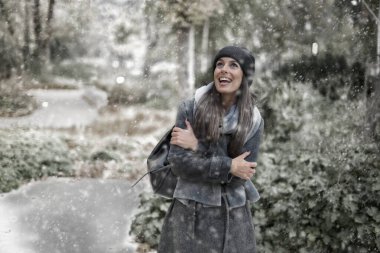 Dışarıda parkta kar yağışı altında duran bir kadın. Şapka ve eşarp takan mutlu bir kadın.. 