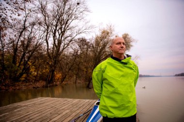 İskelede duran ve kanoya binmeye hazır orta yaşlı bir adam. Aktif sporcu takım elbiseli ve derin düşüncelere dalmış.. 