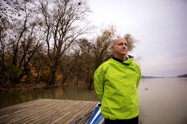 İskelede duran ve kanoya binmeye hazır orta yaşlı bir adam. Aktif sporcu takım elbiseli ve derin düşüncelere dalmış.. 