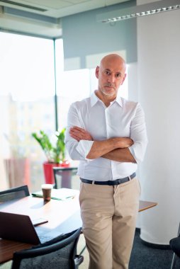 Orta yaşlı profesyonel bir erkek, parlak bir ofiste duruyor. İş kıyafeti giyen profesyonel bir erkek..