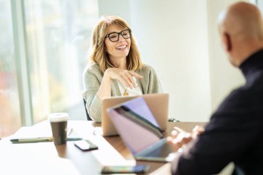 Bir grup iş arkadaşı masa başında oturup iş toplantısı yapıyorlar. Orta yaşlı iş adamları dizüstü bilgisayar kullanıyor ve tartışıyorlardı. Takım çalışması.. 