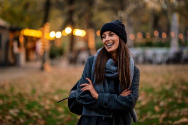 Bir sonbahar günü şehir parkında yürüyen orta yaşlı güzel bir kadın. Beyaz kadın ceketli ve bereli..