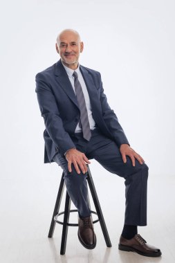 Orta yaşlı bir iş adamının soyutlanmış geçmişine karşı takım elbise giyip kravat takması. Beyaz erkek kameraya bakıyor ve gülümsüyor.. 