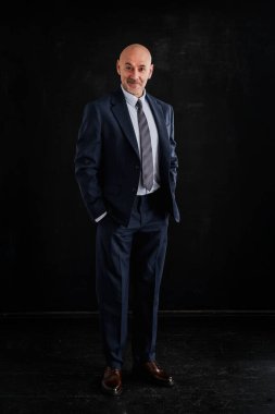 Takım elbise giyen ve izole edilmiş siyah arka plana karşı duran beyaz bir adam. Boşluğu kopyala. 