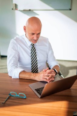 Orta yaşlı bir iş adamının ofis masasında dizüstü bilgisayar kullanırken görüntüsü. Modern bir ofiste çalışan profesyonel bir adam..