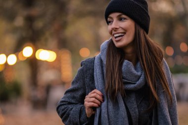 Bir sonbahar günü şehir parkında yürüyen orta yaşlı güzel bir kadın. Beyaz kadın ceketli ve bereli..