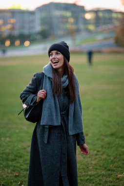 Bir sonbahar günü şehir parkında yürüyen orta yaşlı güzel bir kadın. Beyaz kadın ceketli ve bereli..