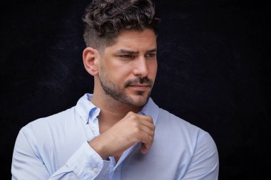 Tecrit edilmiş arka planda düşünceli görünen yakışıklı bir adamın stüdyo fotoğrafı. Gündelik kıyafetler giyen kendinden emin bir erkek. Boşluğu kopyala. 