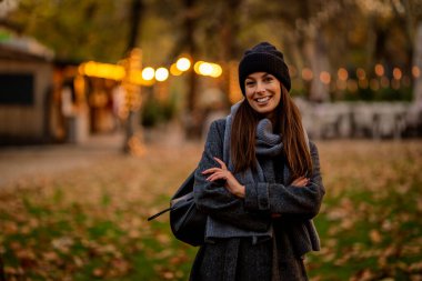 Bir sonbahar günü şehir parkında yürüyen orta yaşlı güzel bir kadın. Beyaz kadın ceketli ve bereli..