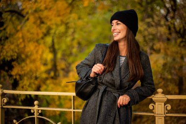 Bir sonbahar günü şehir parkında yürüyen orta yaşlı güzel bir kadın. Beyaz kadın ceketli ve bereli.. 