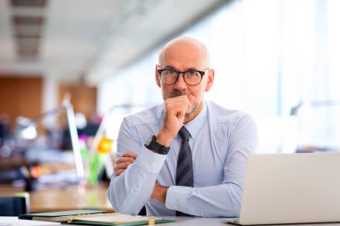 Ofiste oturan kıdemli işadamı. Profesyonel erkek iş için dizüstü bilgisayar kullanıyor.. 