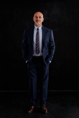 Takım elbise giyen ve izole edilmiş siyah arka plana karşı duran beyaz bir adam. Boşluğu kopyala. 