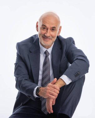 İzole edilmiş arka planda takım elbise giyen ve kravat takan orta yaşlı bir işadamı. Beyaz erkek kameraya bakıyor ve gülümsüyor.. 