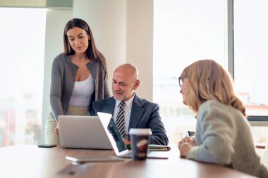 İş arkadaşları toplantıda dizüstü bilgisayar kullanıyor. Takım çalışması. Modern bir ofiste iş adamları toplantı sırasında tartışıyor..