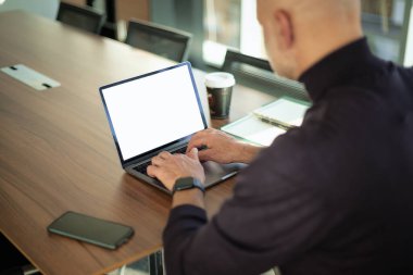 Ofis masasında dizüstü bilgisayarla çalışan iş adamının dikiz görüntüsü. Boş ekran. Omuz manzarasının üstünde.. 