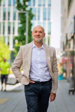 Şehir caddesinde yürüyen orta yaşlı bir adam. Kendine güveni tam bir erkek iş kıyafeti giyiyor.. 