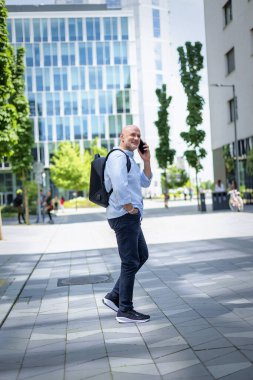 Şehirde iş bölgesinde yürüyen yakışıklı bir adam. Orta yaşlı işadamı iş kıyafeti giyiyor ve telefon görüşmesi yapıyor.. 
