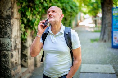 Şehirde dolaşan sıradan bir adam. Orta yaşlı iş adamı sırt çantası takıyor ve telefonla konuşuyor.. 