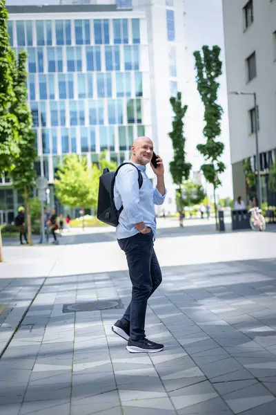 Şehirde iş bölgesinde yürüyen yakışıklı bir adam. Orta yaşlı işadamı iş kıyafeti giyiyor ve telefon görüşmesi yapıyor.. 