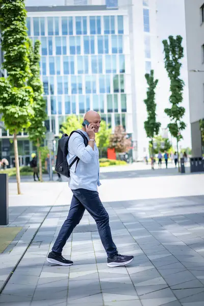 Şehirde iş bölgesinde yürüyen yakışıklı bir adam. Orta yaşlı işadamı iş kıyafeti giyiyor ve telefon görüşmesi yapıyor.. 