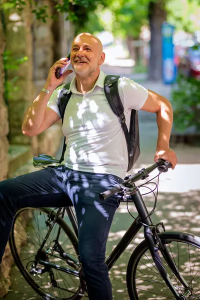 Şehirde bisikletli bir banliyö. Son sınıf öğrencisi sokakta bisiklet sürüyor ve akıllı telefonunu kullanıyor. Gündelik giysiler ve sırt çantası giyen kendinden emin bir erkek.. 