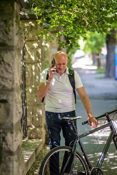 Şehirde bisikletli bir banliyö. Son sınıf öğrencisi sokakta bisiklet sürüyor ve akıllı telefonunu kullanıyor. Gündelik giysiler ve sırt çantası giyen kendinden emin bir erkek.. 