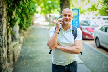 Şehirde dolaşan sıradan bir adam. Orta yaşlı iş adamı sırt çantası takıyor ve telefonla konuşuyor.. 