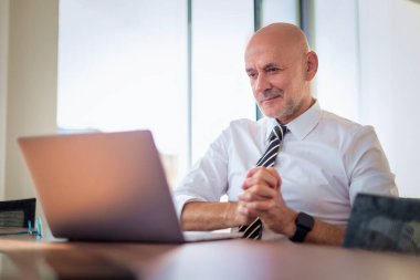 Ofis masasında dizüstü bilgisayar kullanan bir iş adamı. Modern bir ofiste çalışan profesyonel bir adam..