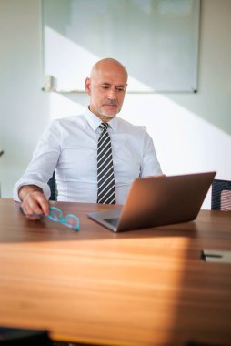 Ofis masasında dizüstü bilgisayar kullanan bir iş adamı. Modern bir ofiste çalışan profesyonel bir adam..