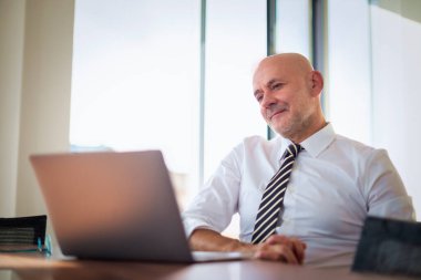 Ofis masasında dizüstü bilgisayar kullanan bir iş adamı. Modern bir ofiste çalışan profesyonel bir adam..