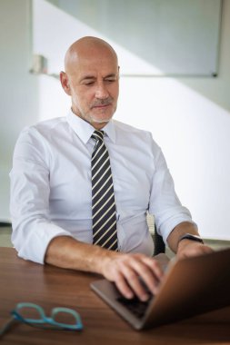 Ofis masasında dizüstü bilgisayar kullanan bir iş adamı. Modern bir ofiste çalışan profesyonel bir adam..