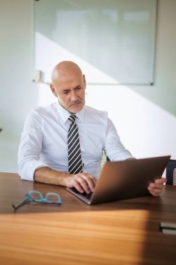 Ofis masasında dizüstü bilgisayar kullanan bir iş adamı. Modern bir ofiste çalışan profesyonel bir adam..
