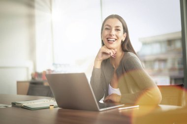 Ofis masasında çalışırken bilgisayarını kullanan çekici bir iş kadını. İş kıyafeti giyen profesyonel bir kadın.. 