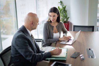 Bir grup iş arkadaşı masada oturuyor ve iş toplantısı yapıyorlar. Orta yaşlı iş adamları dizüstü bilgisayar kullanıyor ve tartışıyorlardı. Takım çalışması.. 
