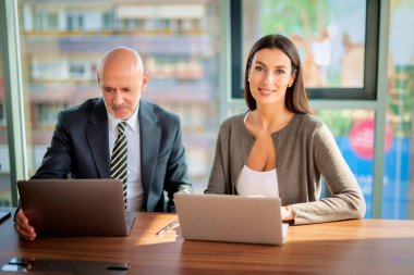 Bir grup iş arkadaşı masada oturuyor ve iş toplantısı yapıyorlar. Orta yaşlı iş adamları dizüstü bilgisayar kullanıyor ve tartışıyorlardı. Takım çalışması.. 
