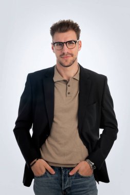 Beyaz arka planda duran yakışıklı bir iş adamının stüdyo fotoğrafı. Polo tişört ve spor ceket giyen kendinden emin bir erkek. Uzayı kopyala İzole edilmiş arkaplan.