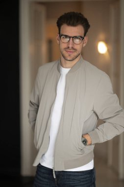 Kameraya bakıp gülümseyen genç bir adamın vesikalığı. Beyaz gömlek ve ceket giyen ve içeride duran kendine güvenen bir adam.. 