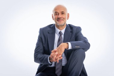 Soyutlanmış arka planda takım elbise giyen ve kravat takan orta yaşlı bir işadamı. Beyaz erkek kameraya bakıyor ve gülümsüyor.. 