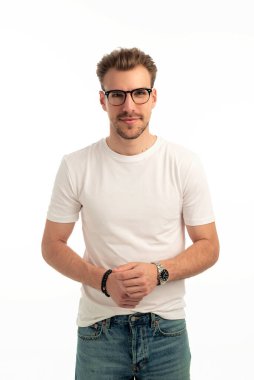 İzole edilmiş arka planda duran genç bir adamın stüdyo çekimi. Beyaz tişört ve kot pantolon giyen kendinden emin bir erkek. Boşluğu kopyala.  