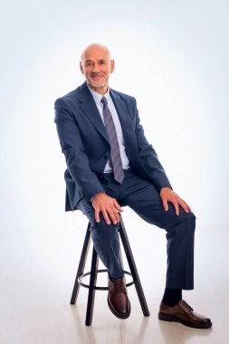 Orta yaşlı bir iş adamının soyutlanmış geçmişine karşı takım elbise giyip kravat takması. Beyaz erkek kameraya bakıyor ve gülümsüyor.. 