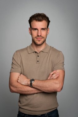 Tecrit edilmiş arka planda duran yakışıklı bir gencin stüdyo fotoğrafı. Polo tişört giyen ve kameraya bakan kendinden emin bir erkek. Uzayı kopyala İzole edilmiş arkaplan. 