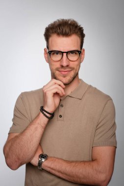 Tecrit edilmiş arka planda duran yakışıklı bir gencin stüdyo fotoğrafı. Polo tişört giyen ve kameraya bakan kendinden emin bir erkek. Uzayı kopyala İzole edilmiş arkaplan. 