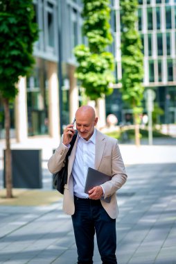 Şehirde iş bölgesinde yürüyen yakışıklı bir adam. Orta yaşlı işadamı iş kıyafeti giyiyor ve telefon görüşmesi yapıyor.. 